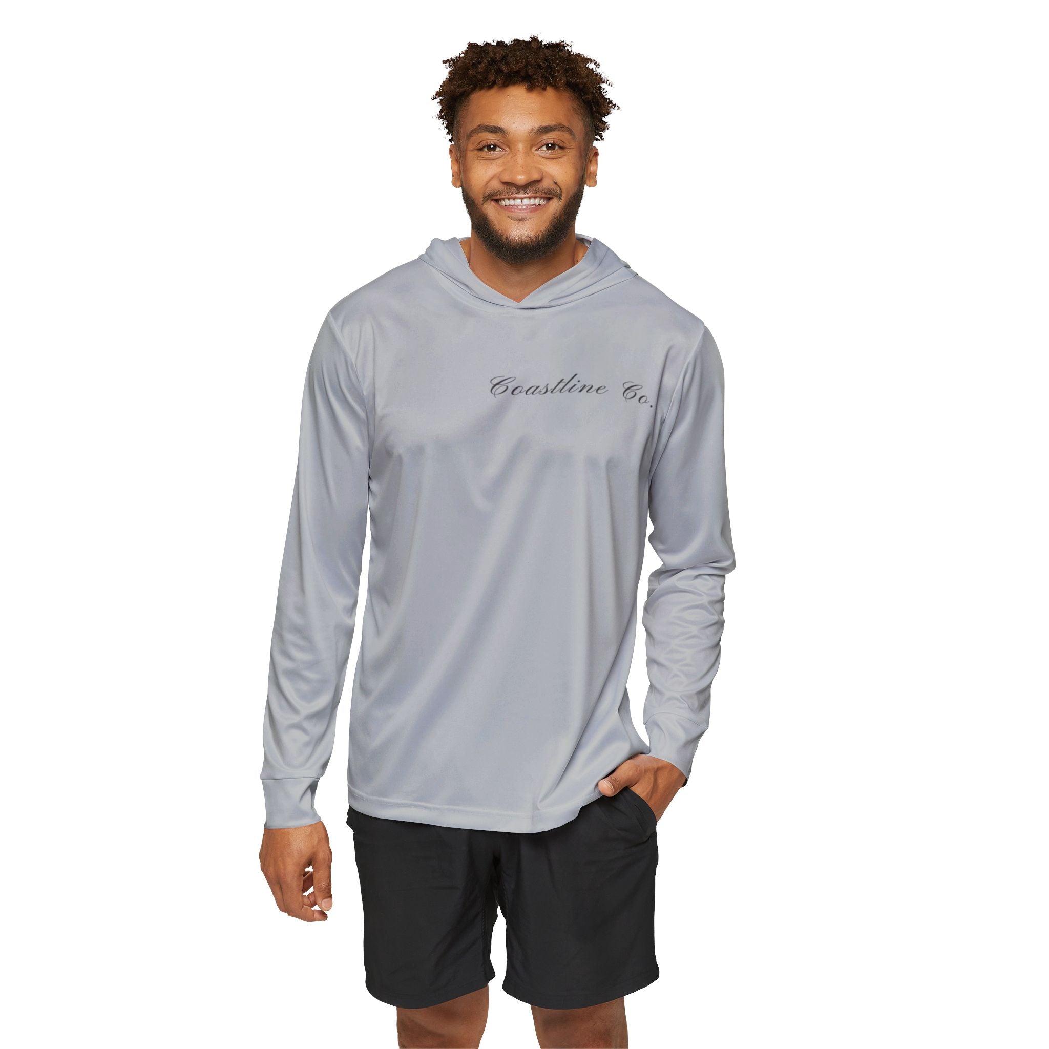 A man wearing a light gray long-sleeve hooded performance shirt with 'Carolina Co.' printed in black script on the chest, paired with black athletic shorts, against a plain white background.
